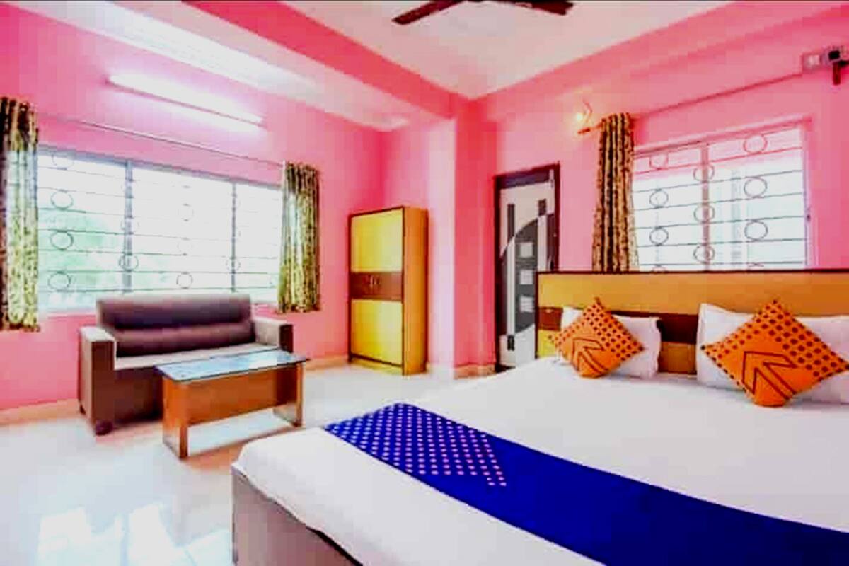 A bedroom with a bed, a sofa, a wardrobe, and a window with curtains.
