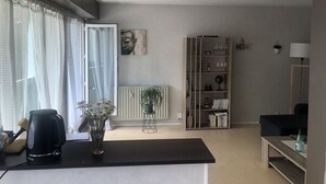 Moderni olohuone, jossa on musta sohvapöytä, kirjahylly, patteri ja ikkuna, jossa on verhot.