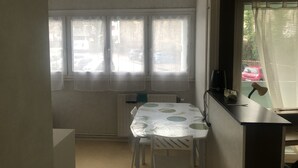 Pieni ruokailutila, jossa on pöytä ja tuolit, patteri ja ikkuna, jossa on verhot.