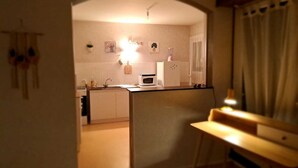 Pieni, käytännöllinen keittiö, jossa on valkoiset kaapit, mikroaaltouuni ja jääkaappi.