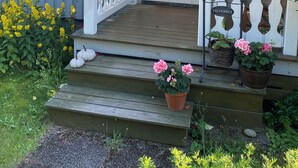 Eine Veranda mit weißer Reling, einem Willkommensschild und hängenden Blumenkörben.