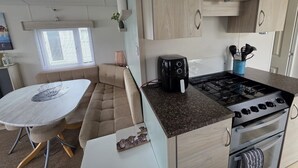 Cocina compacta con estufa a gas, horno y una pequeña mesa de comedor con un banco acolchado.