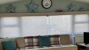 Un salón acogedor con un sofá, un reloj, decoraciones de estrellas y un modelo de furgoneta en el alféizar de la ventana.