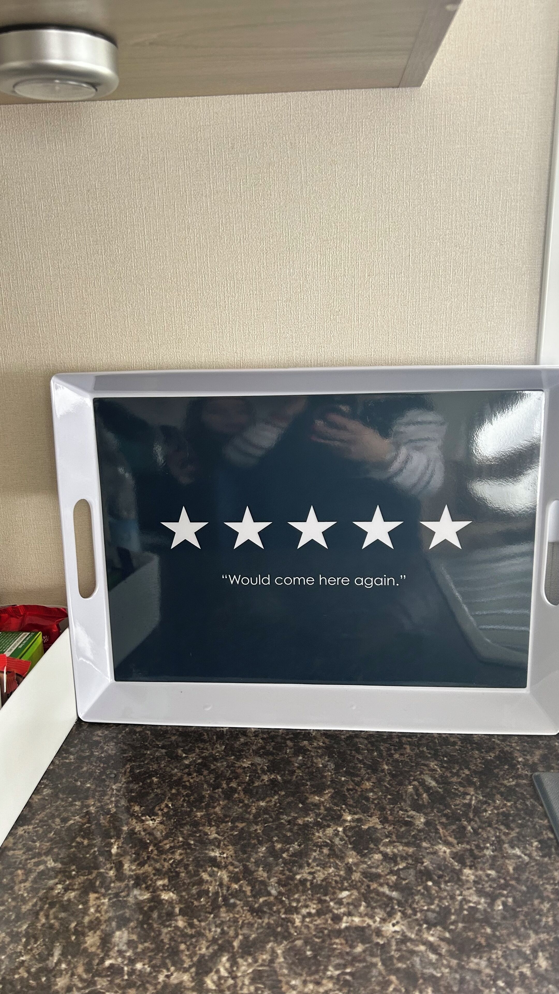 A microwave with a reflective surface displaying a star rating and a quote.