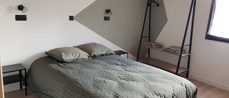 Un dormitorio moderno con una cama, dos mesitas de noche, una silla colgante y un ventanal.