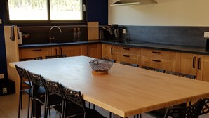 Una cocina moderna con una mesa de madera y sillas negras, horno empotrado y ventana con vistas a árboles.
