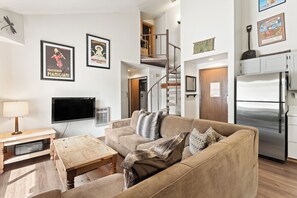 A living room with a sofa, coffee table, TV, and a staircase leading to an upper level.