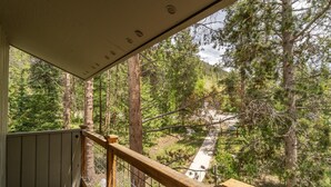 A balcony with a view of a forested area and a paved path. - Conveniently Located in West Keystone with Private Balcony & Gas Fireplace! (Keystone)