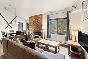 A modern living room with a sofa, coffee table, TV, and a wooden accent wall.