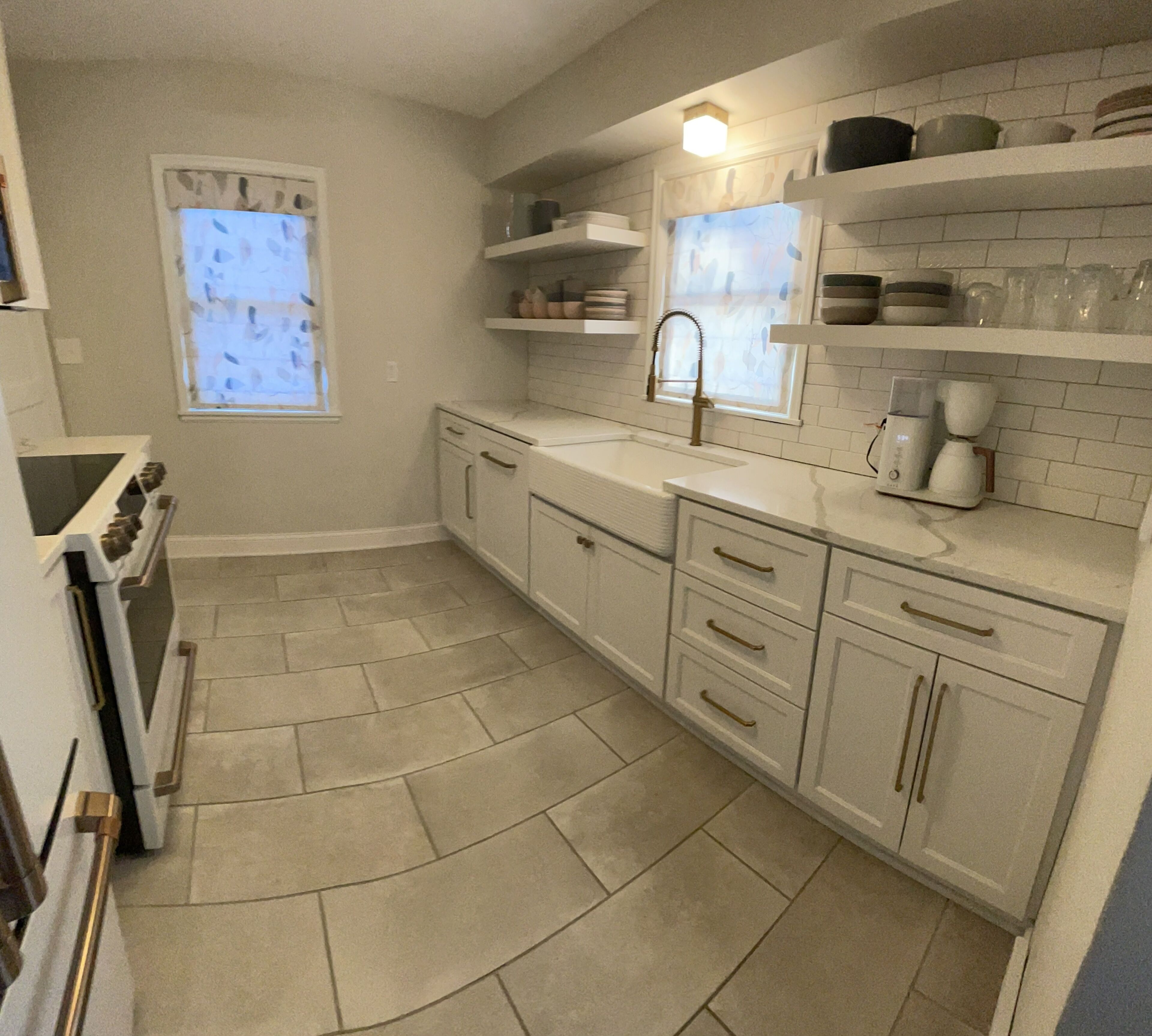 A kitchen with white cabinets, a sink, a stove, and a coffee maker.