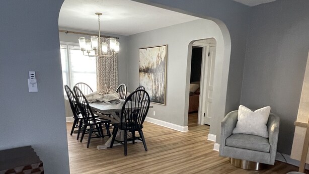 A modern living room with a grey sofa, a patterned rug, and a dining area with a chandelier. - The Warm & Inviting Place (Sioux Falls)