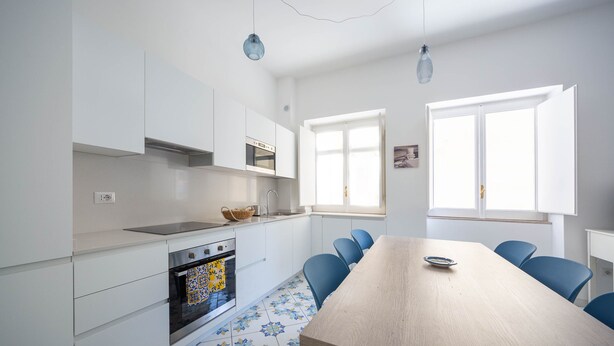 Una cocina moderna con armarios blancos, una mesa de comedor de madera y sillas azules.