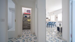 Un pasillo con baldosas de diseño que conduce a un comedor con sillas azules y una mesa.