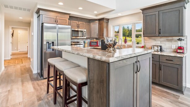 Una cocina moderna con una isla grande, electrodomésticos de acero inoxidable y armarios de madera oscura.