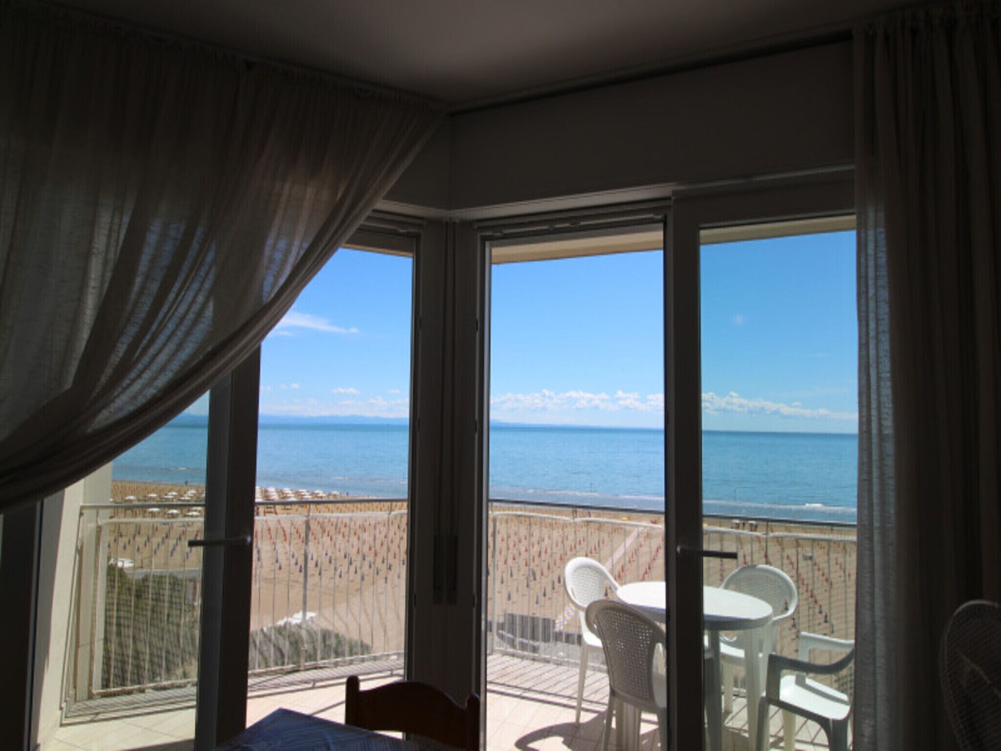 Un balcón con vista al mar, una cama y una mesa con sillas.