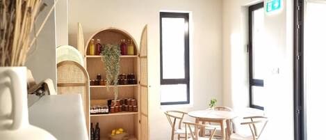 Interior moderno com área de jantar central, mobiliário de madeira e estante embutida com diversos objetos.