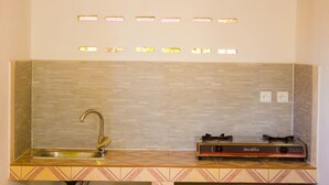 Una cocina con un fregadero, estufa y salpicadero con varias luminarias.