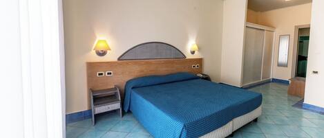 A bedroom with a bed, nightstand, wall-mounted lamps, and a wardrobe.