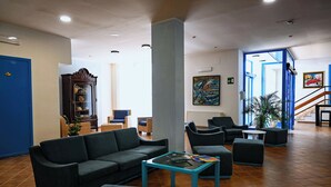 En rummelig lobby med en blå dør, et stort træskab, behagelige siddepladser og en trappe til et andet område.