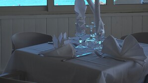 Et spisebord dækket til to med udsigt til havet gennem store vinduer.