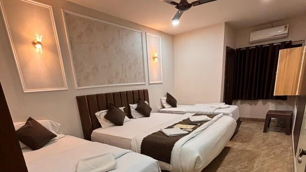 Une chambre d’hôtel avec trois lits, un ventilateur de plafond, des lampes fixées au mur et un appareil de climatisation.