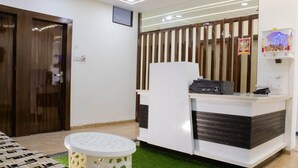 Un espace d’accueil avec un comptoir blanc, une petite table ronde et une cloison en bois.