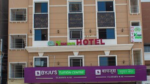 Un hôtel avec une enseigne indiquant « Kiwi Inn Hotel » et, en dessous, un centre de tutorat « Byju's ».