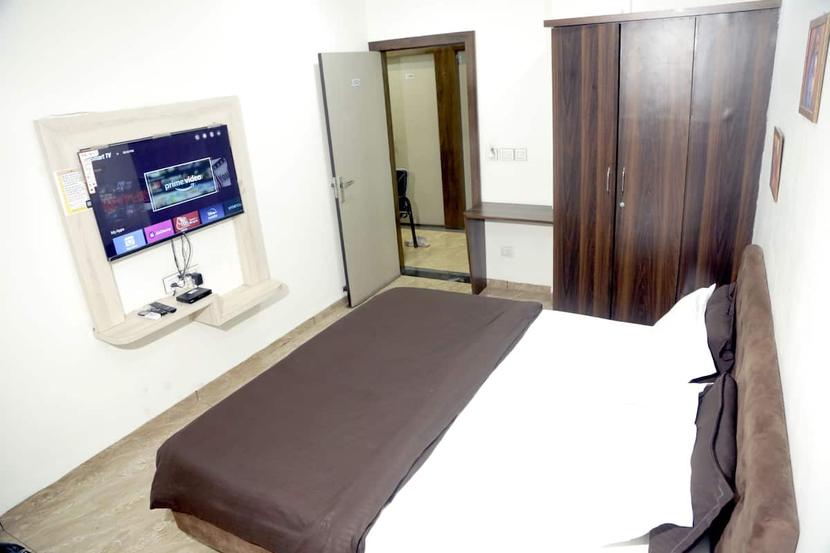 Quarto com cama, guarda-roupa e televisão na parede.