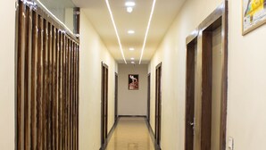 Un long couloir bien éclairé, doté d’un sol brillant, de portes en bois et d’une cloison en verre d’un côté.