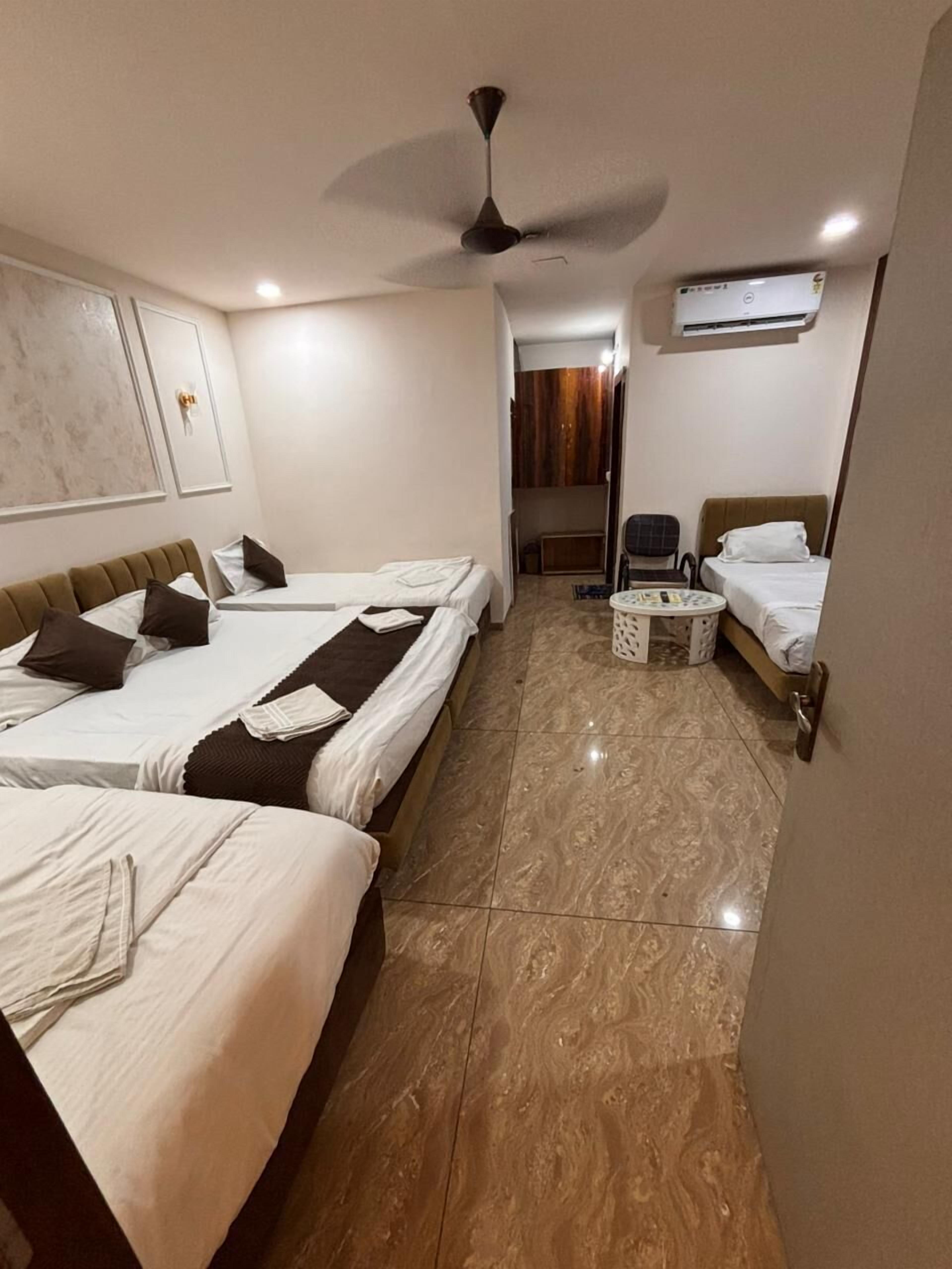 Une chambre d’hôtel avec deux lits, un ventilateur de plafond, un appareil de climatisation et une petite table avec une chaise.