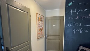 Een gang met een deur, een poster aan de muur en een schoolbord met tekst.