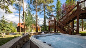 Ett bubbelbad i ett vackert utomhusområde med ett trädäck och stenmurar.