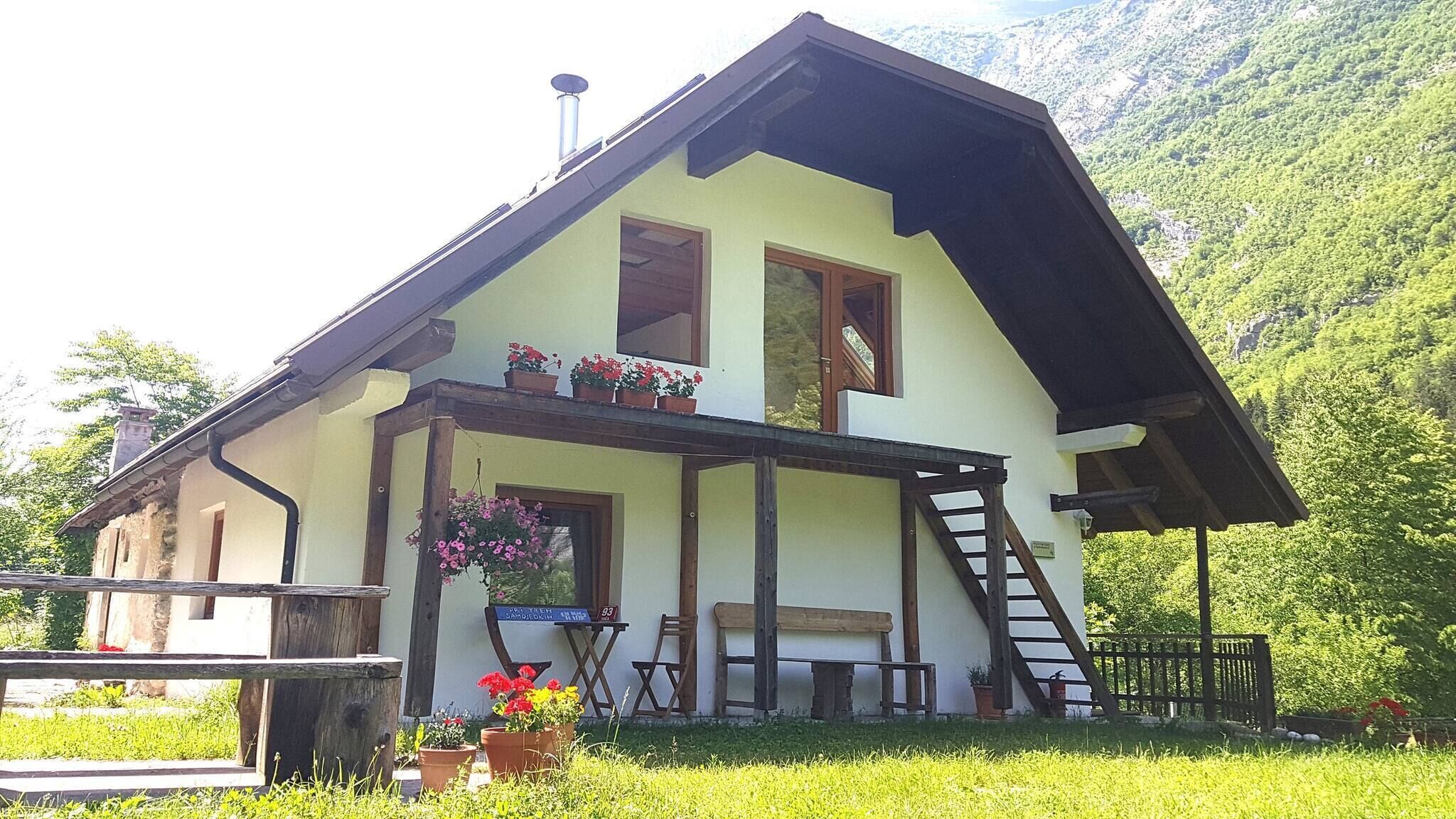 Une maison à deux étages dotée d’un balcon, d’un escalier en bois et offrant une vue sur un paysage montagneux.