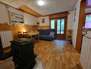A cozy room with a dining table, chairs, a sofa, a radiator, and a wooden ceiling. - Soča Home With The View (Bovec)
