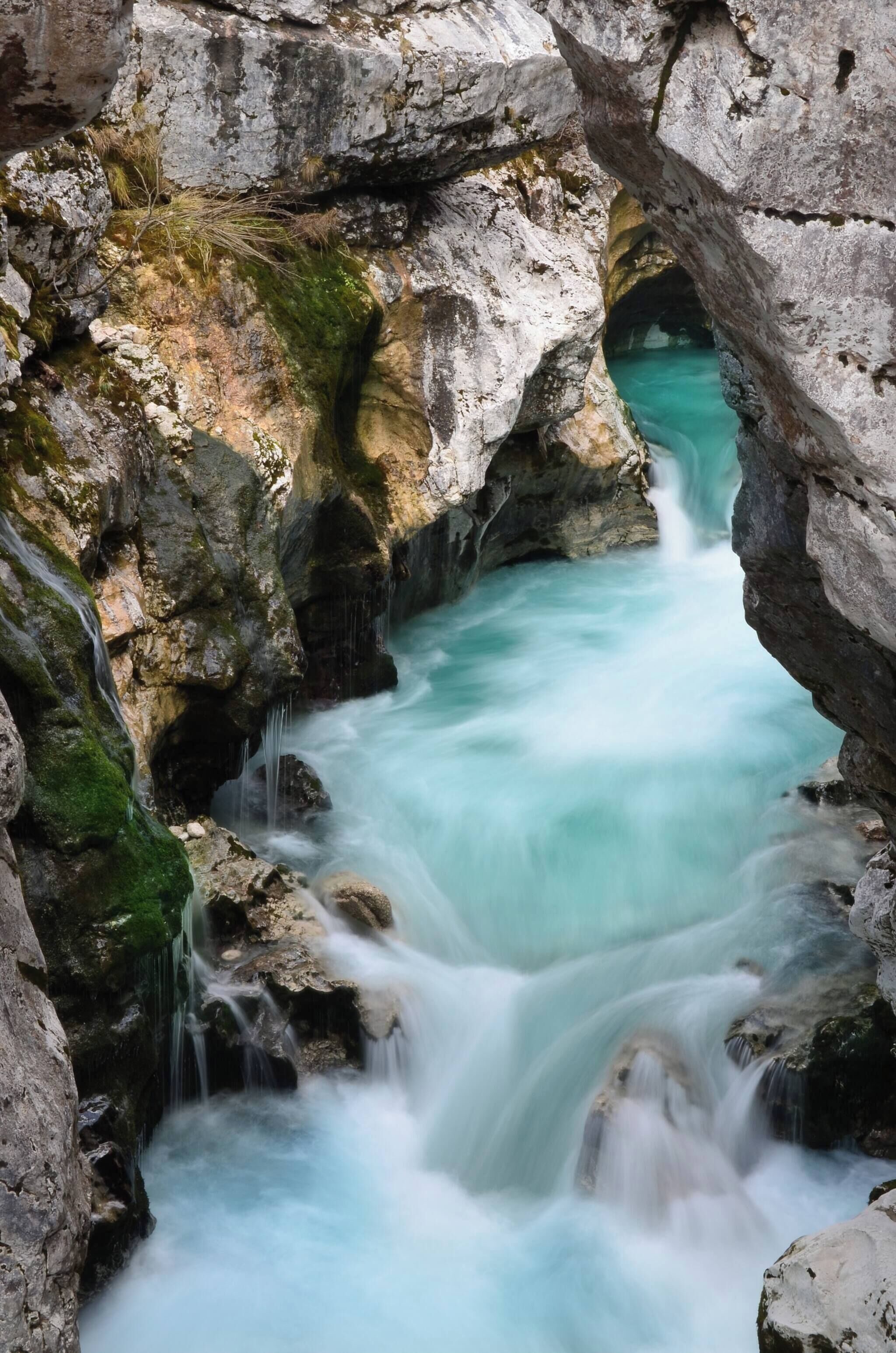 Une formation rocheuse naturelle traversée par un ruisseau aux eaux turquoise.