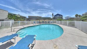 A swimming pool with lounge chairs and a white fence surrounding it. - Relax Inn - Seamist 156 (Port Aransas)