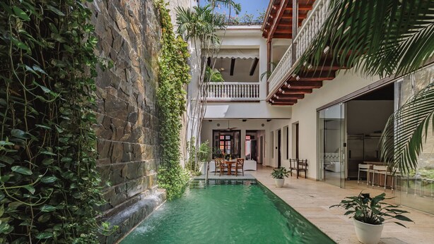 Un patio con piscina, muros de piedra y un balcón con barandilla de madera.