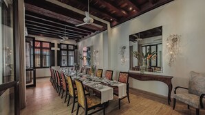 Comedor con una mesa larga dispuesta para varios comensales, pisos de madera y un techo alto con vigas a la vista.