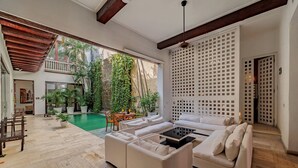 Amplia sala de estar con piscina, sofás blancos y techo de madera.