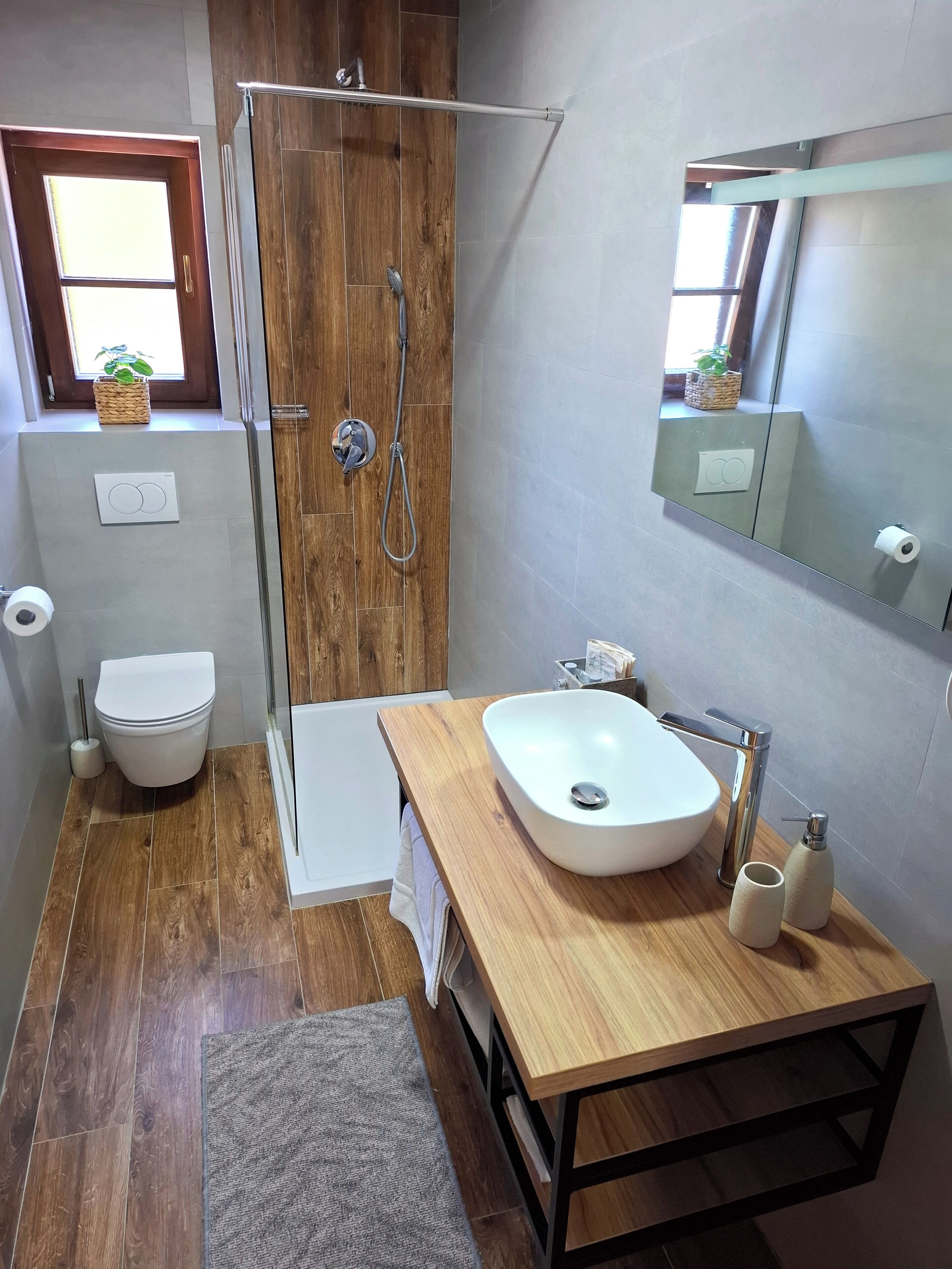 A modern bathroom with a wooden shower, a white sink, and a toilet.