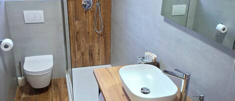 A modern bathroom with a wooden shower, a white sink, and a toilet.