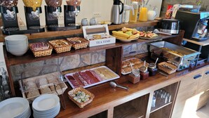 Un bufé de desayuno con diversos alimentos, máquinas de café y aderezos.