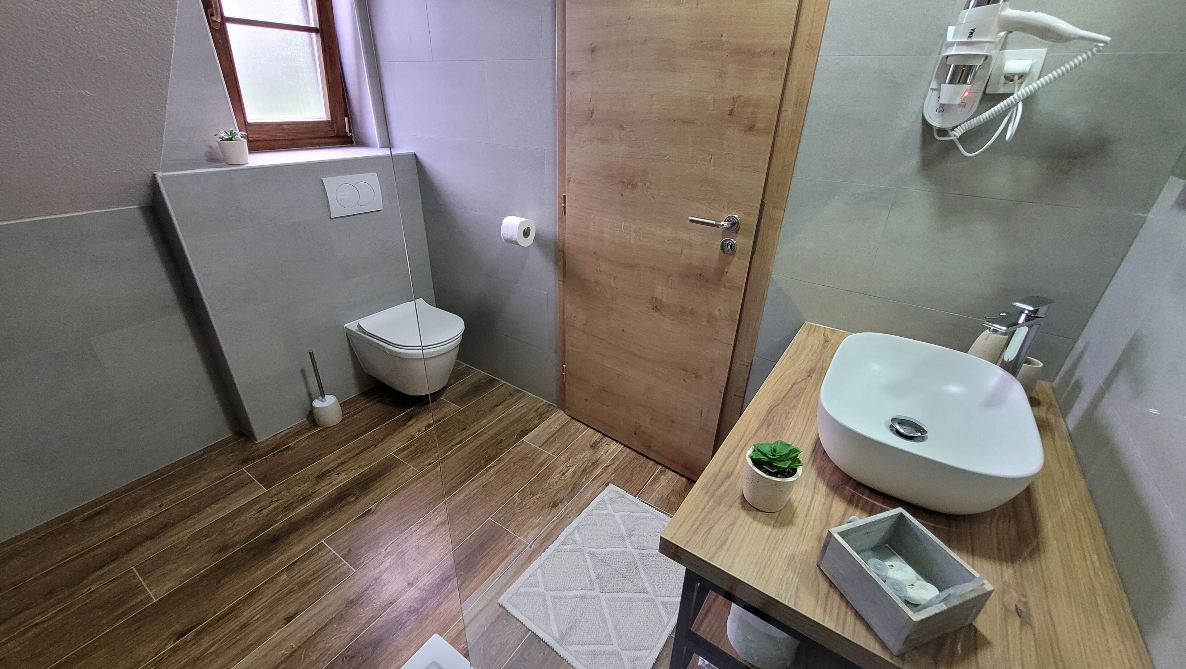 Ein Badezimmer mit Holzboden, Toilette, Waschbecken und Dusche.