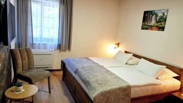 Habitació d'hotel amb llit, cadira, taula petita i un calefactor.