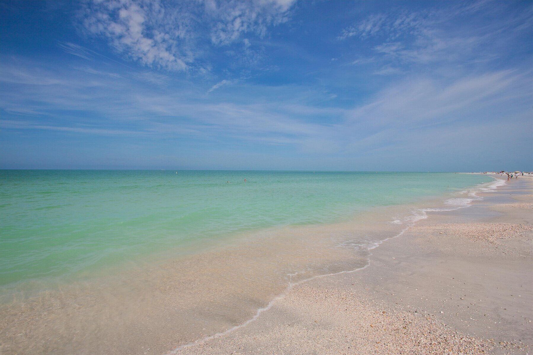 A beach with clear turquoise water and a sandy shore.