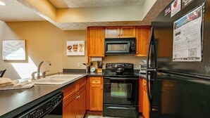A modern kitchen with wooden cabinets, a black refrigerator, a microwave, and a dishwasher. - Deep Creek Fun w/ Hot Tub, Dock & Fireplace (McHenry)