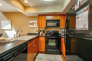 A modern kitchen with wooden cabinets, a black refrigerator, a microwave, and a dishwasher.