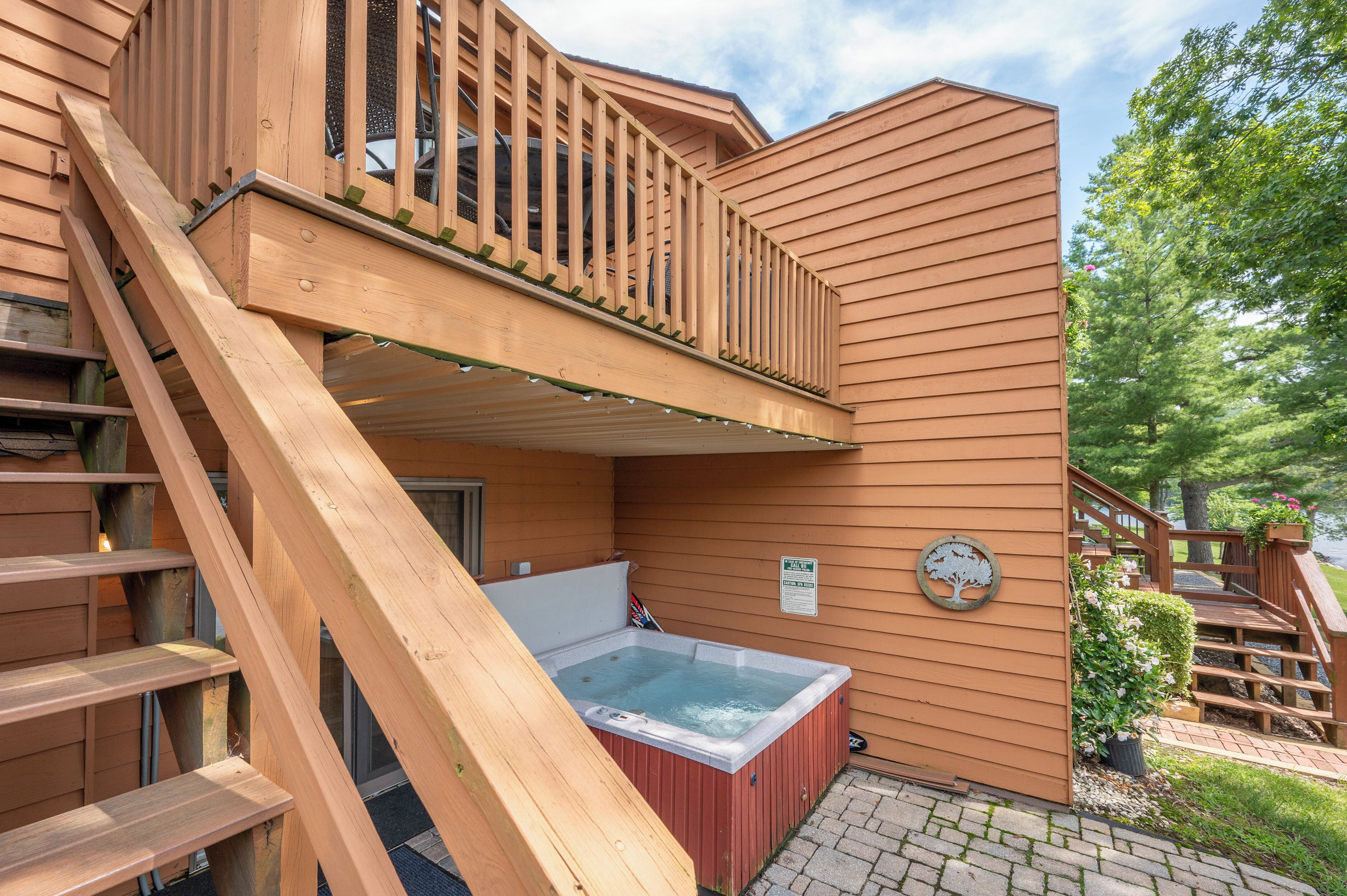 Une terrasse en bois avec un jacuzzi, un escalier et une vue sur un lac.