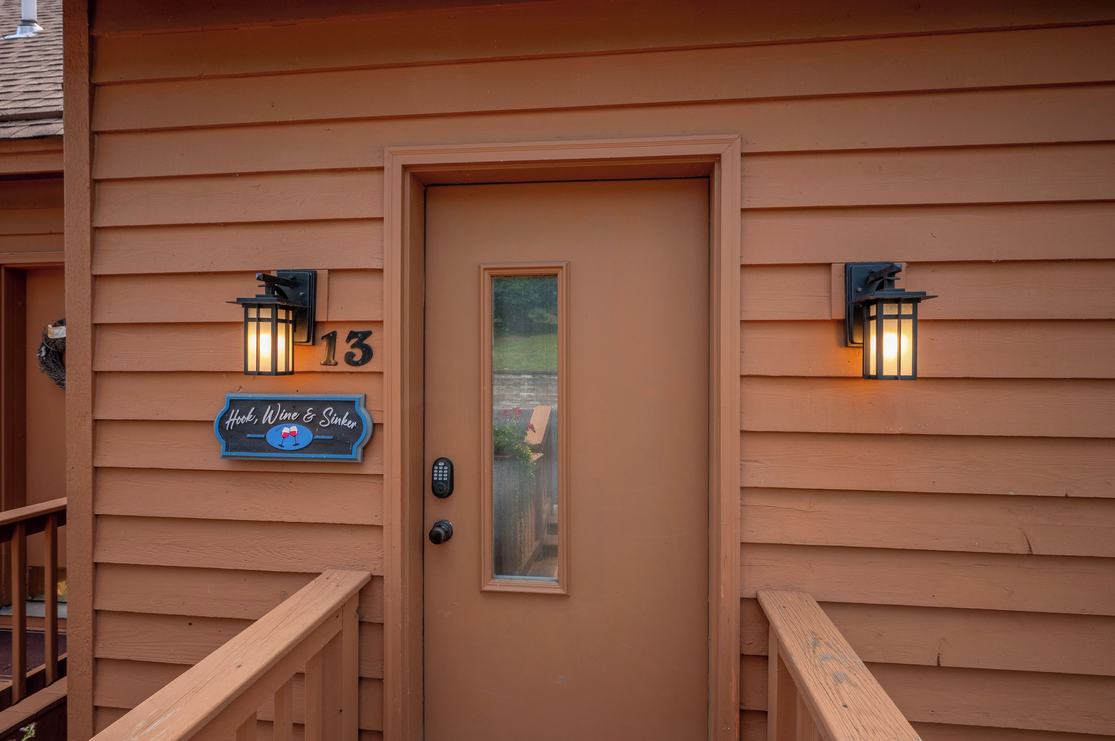 A wooden door with a number 13 sign, a small window, and two wall-mounted lights.