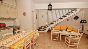 Eine Küche mit Esstisch und Stühlen, einer Treppe und einem Wohnbereich mit Sofa und Lampe.